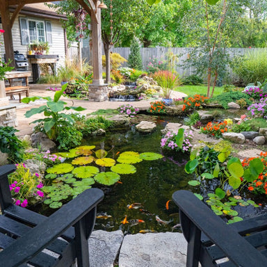 Aquascape 11′x16′ Medium Pond Kit - Backyard garden with a pond, flowers, and chairs