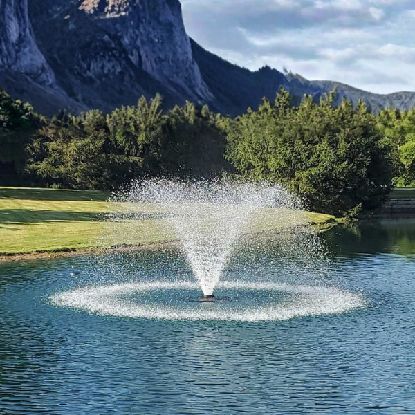 Aerating Pond Fountain in a pond at a golf course with mountains in the background - Benefits of Pond Aeration