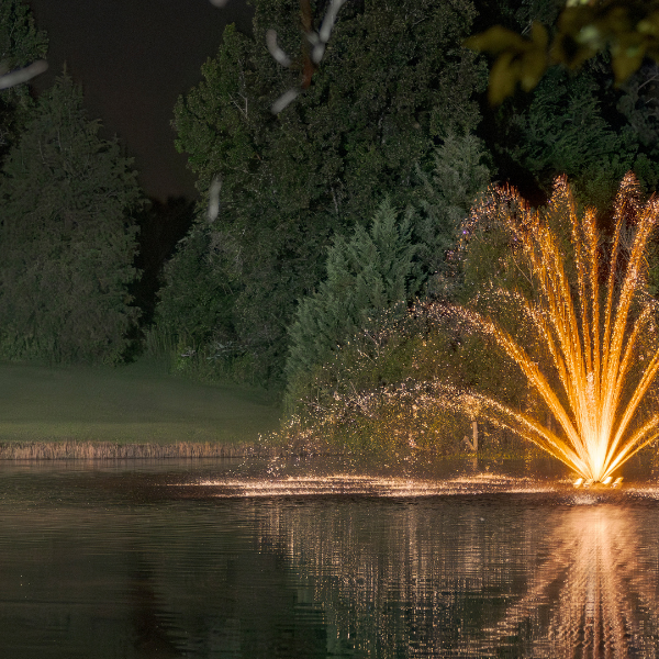 Fishing lodge with a fountain with lighting at night on a pond - Are Fountains Good for Ponds?