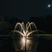 Kasco Composite LED Light Kit creating warm white illuminated fountain spray under moonlit night sky