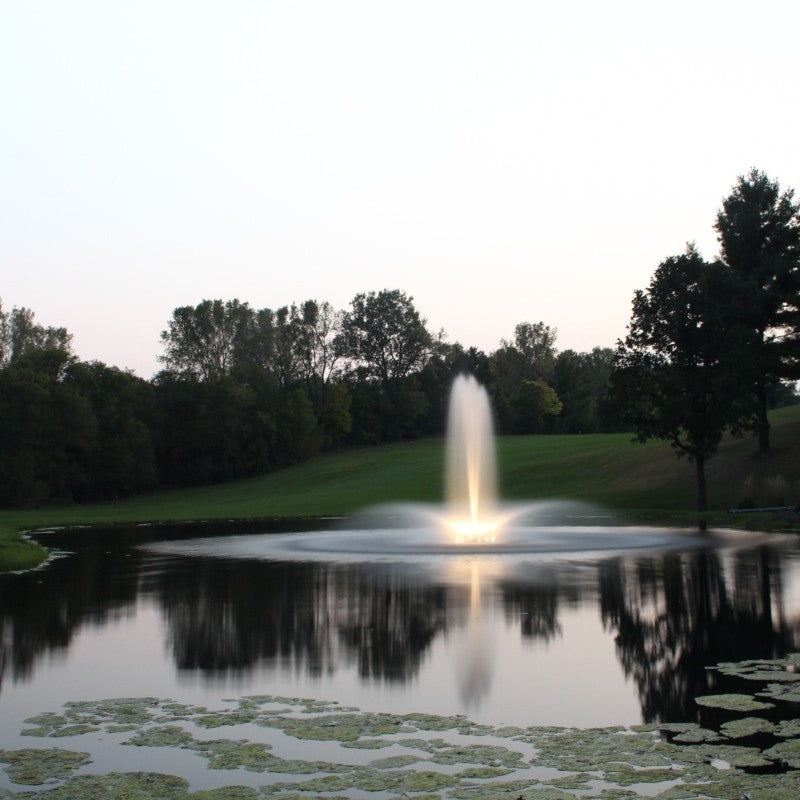Kasco Composite LED Light Kit lighting a vertical fountain display in a calm pond during dusk