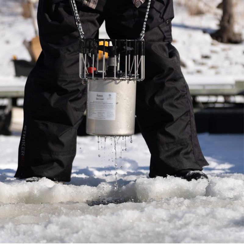 Kasco De-Icer being lowered through an ice hole by a person standing on frozen water during winter installation