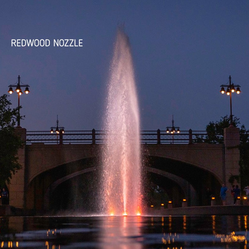 Kasco J Series Fountain with Redwood Nozzle illuminated at night with orange lighting near a bridge