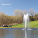 Kasco J Series Fountain with Sequoia Nozzle spray pattern in daytime golf course pond setting with golf carts