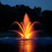 Kasco Mahogany Fountain Masterpiece Bundle illuminated at night with orange lighting in golf course pond setting
