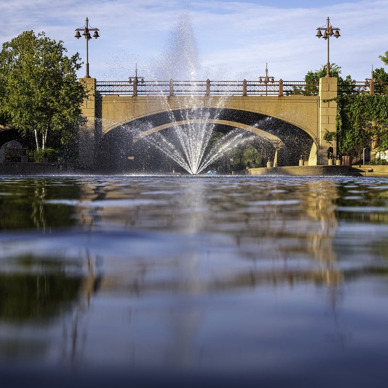 Kasco Mahogany Fountain Masterpiece Bundle spray pattern in daytime urban waterway near historic bridge