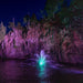 Kasco Mahogany Fountain illuminated at night with teal and purple lighting near rocky cliff