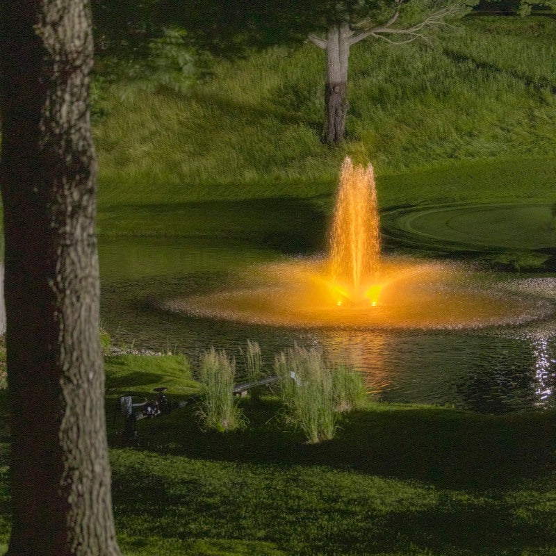 Kasco RGBW LED Lighting - RGBW18 LED Lighting System illuminating a pond fountain in warm golden light at night
