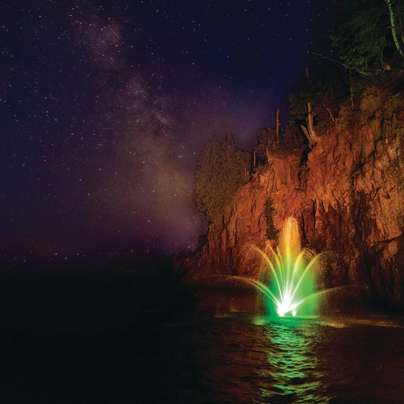 Kasco RGB LED Lighting illuminating a decorative pond fountain with vibrant multicolor display under a starry night sky