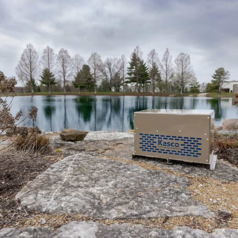 Kasco Robust Aire compressor cabinet installed beside pond shoreline with lake and trees in background