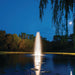 Kasco Stainless Steel LED Light Kit lighting a vertical pond fountain with bright white illumination under a moonlit sky