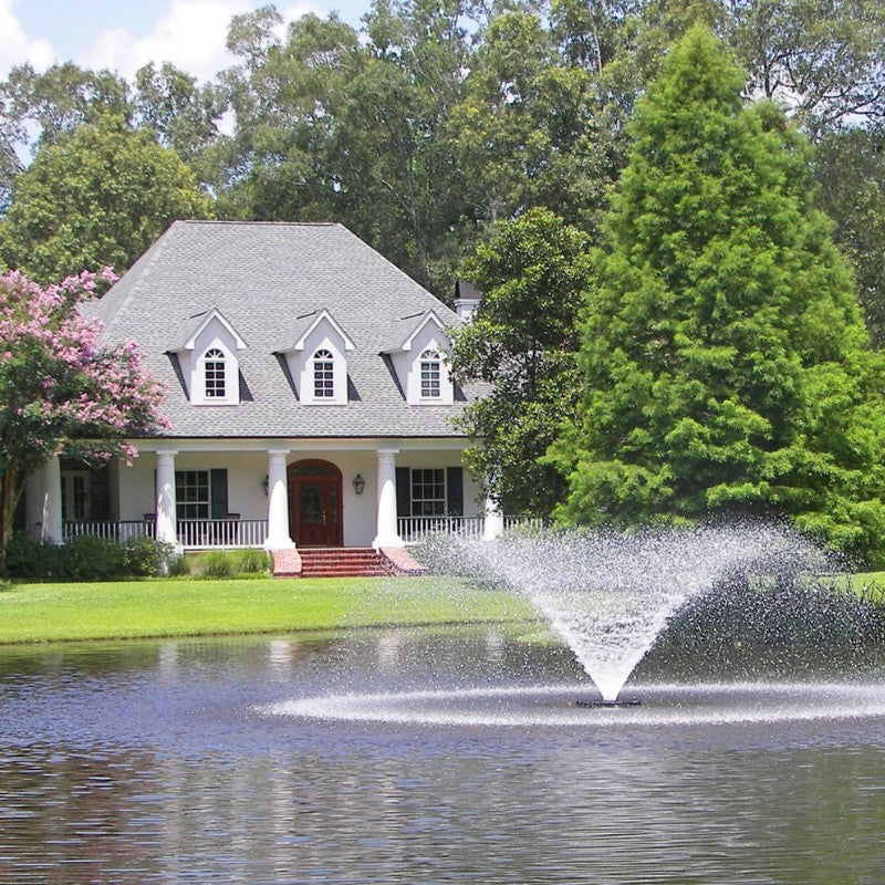 Kasco VFX Aerating Fountain creating a wide spray pattern in a landscaped pond in front of a residential home