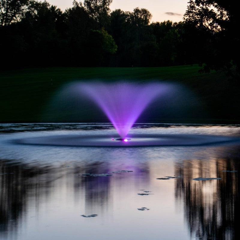 Kasco VFX Aerating Fountain illuminated with purple LED lights reflecting on a calm pond at dusk
