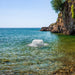 Kasco surface aerator creating strong water agitation in a clear coastal water setting near rocky shoreline