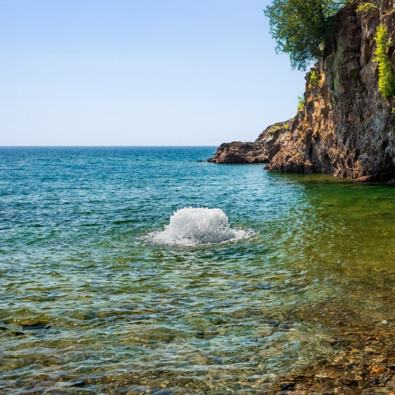 Kasco surface aerator creating strong water agitation in a clear coastal water setting near rocky shoreline