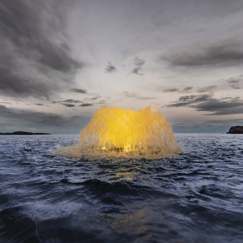 Kasco surface aerator producing an illuminated spray pattern in open water during evening operation