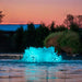 Kasco surface aerator with teal LED lighting in pond at dusk