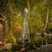 Outdoor Water Solutions Decorative Backyard Windmill installed among trees and landscaping in a residential yard