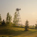 Outdoor Water Solutions Super Premier Windmill Pond Aerator installed on a landscaped hill with trees and grass