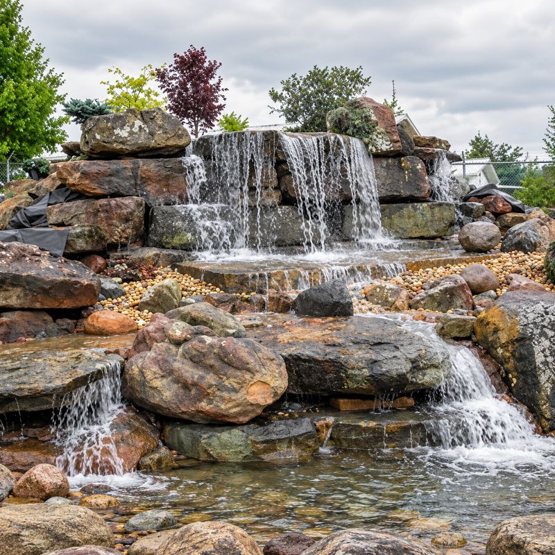 Savio Pond Free Waterfall Packages completed tiered rock waterfall with multiple cascading drops, natural stones, and pebble landscaping