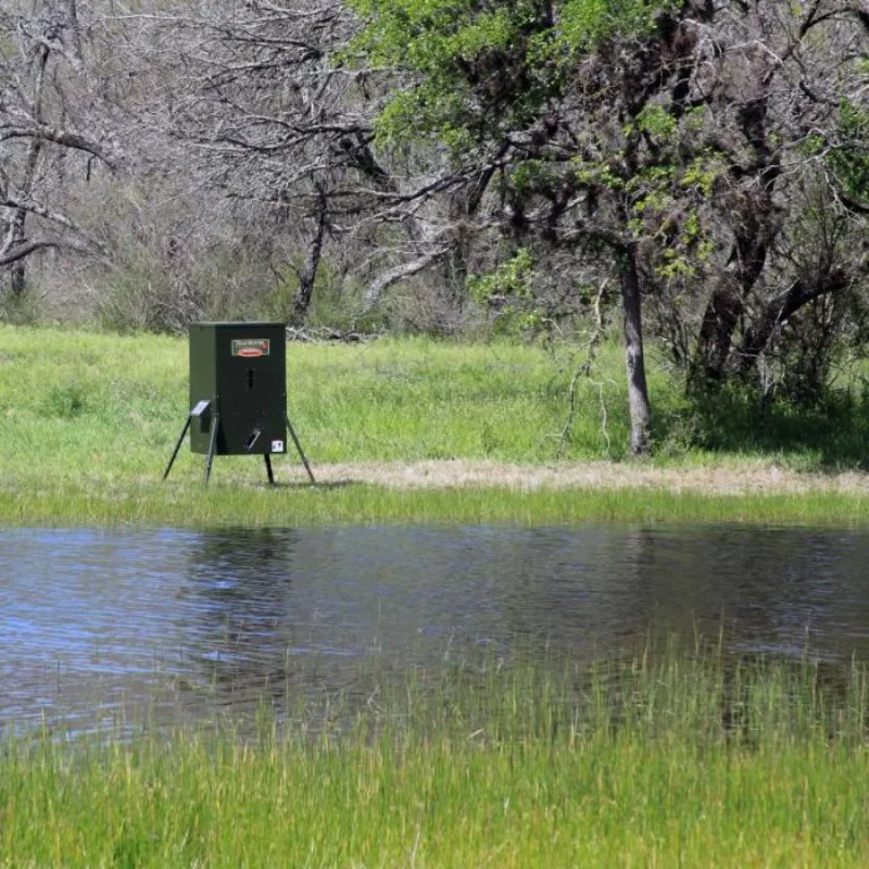 Texas Hunter Fish Feeder - 250 lbs unit with adjustable legs installed beside the pond
