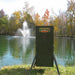 Texas Hunter Fish Feeder - 70 lbs unit with adjustable legs with a fountain at the background